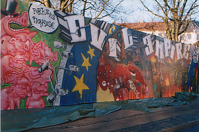 Graffiti tekstillä "Evil Empire", sotakoneita, köyhiä ja rikkaita sikoja...